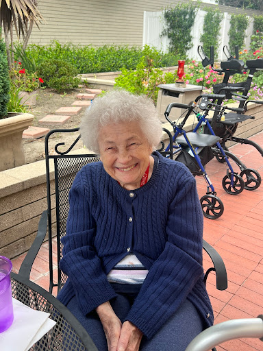 A joyful elderly woman enjoying a sunny day in the garden.