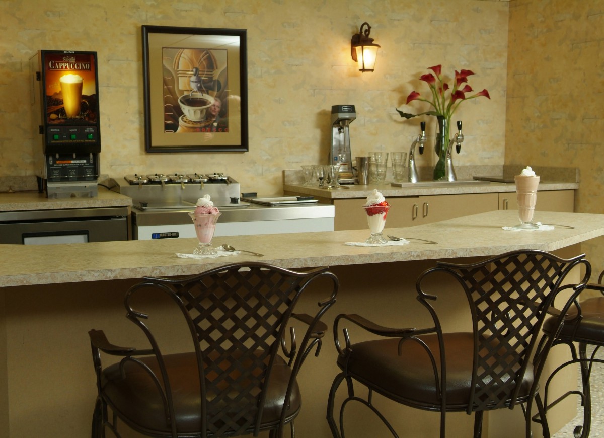 A cozy cafe counter with barstools, ice cream cones, and decorative flowers.