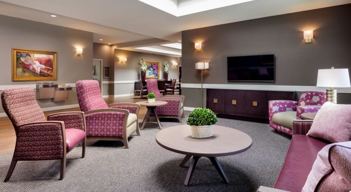 A cozy lounge area featuring comfortable seating, a coffee table with a plant, and a television on the wall.