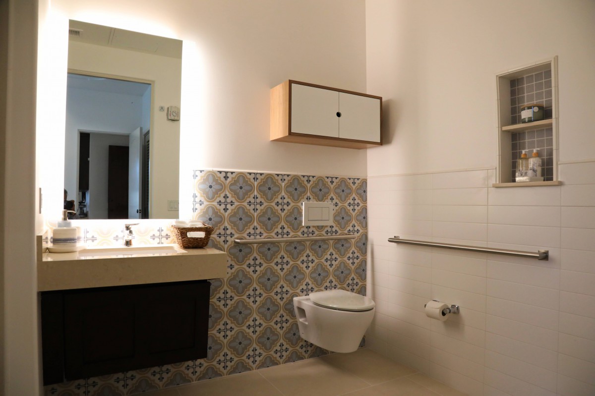 Modern bathroom with patterned tiles and wall-mounted fixtures.