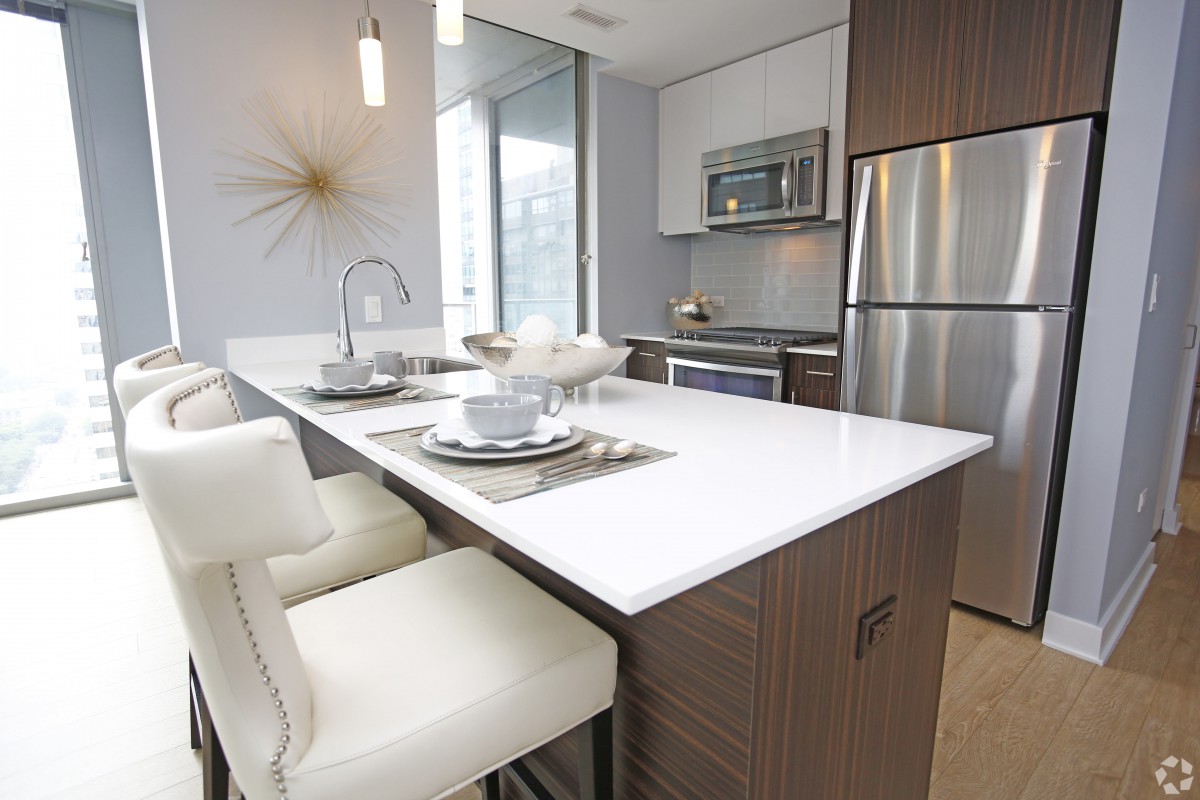 A modern kitchen with sleek design featuring a white countertop and stainless steel appliances.