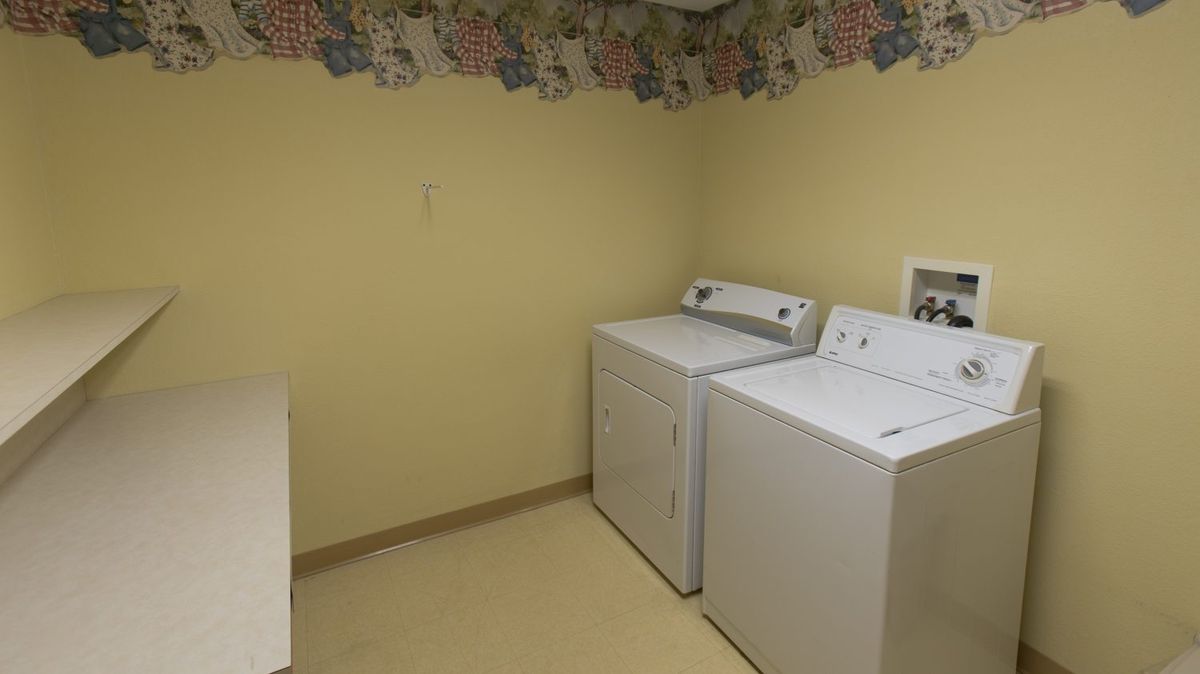 A simple laundry room with a washer and dryer set against a floral-themed wallpaper.