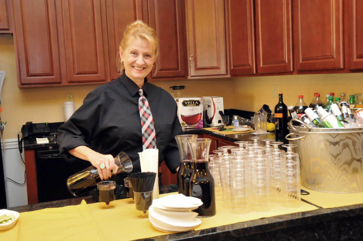 A bartender preparing drinks in a kitchen setup for an event.