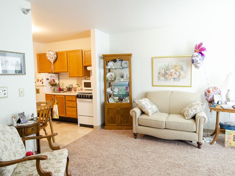 A cozy living area with a sofa, decorative cabinet, and a view into the adjacent kitchen space.