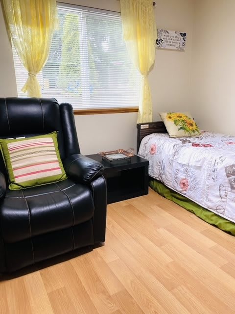 A cozy bedroom with a single bed and a comfortable leather chair.