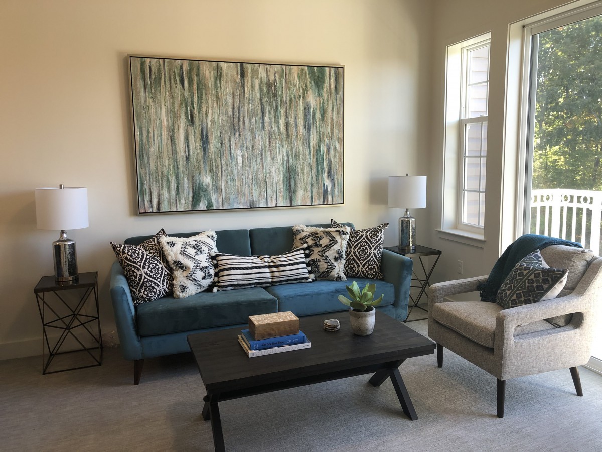 A cozy living room featuring a modern sofa with decorative pillows, a large abstract painting on the wall, and a stylish coffee table.