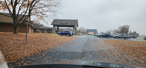 A view of a parking area surrounded by fallen leaves under a cloudy sky.