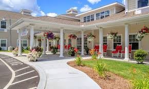 A charming building with a spacious porch adorned with flowers and outdoor seating.