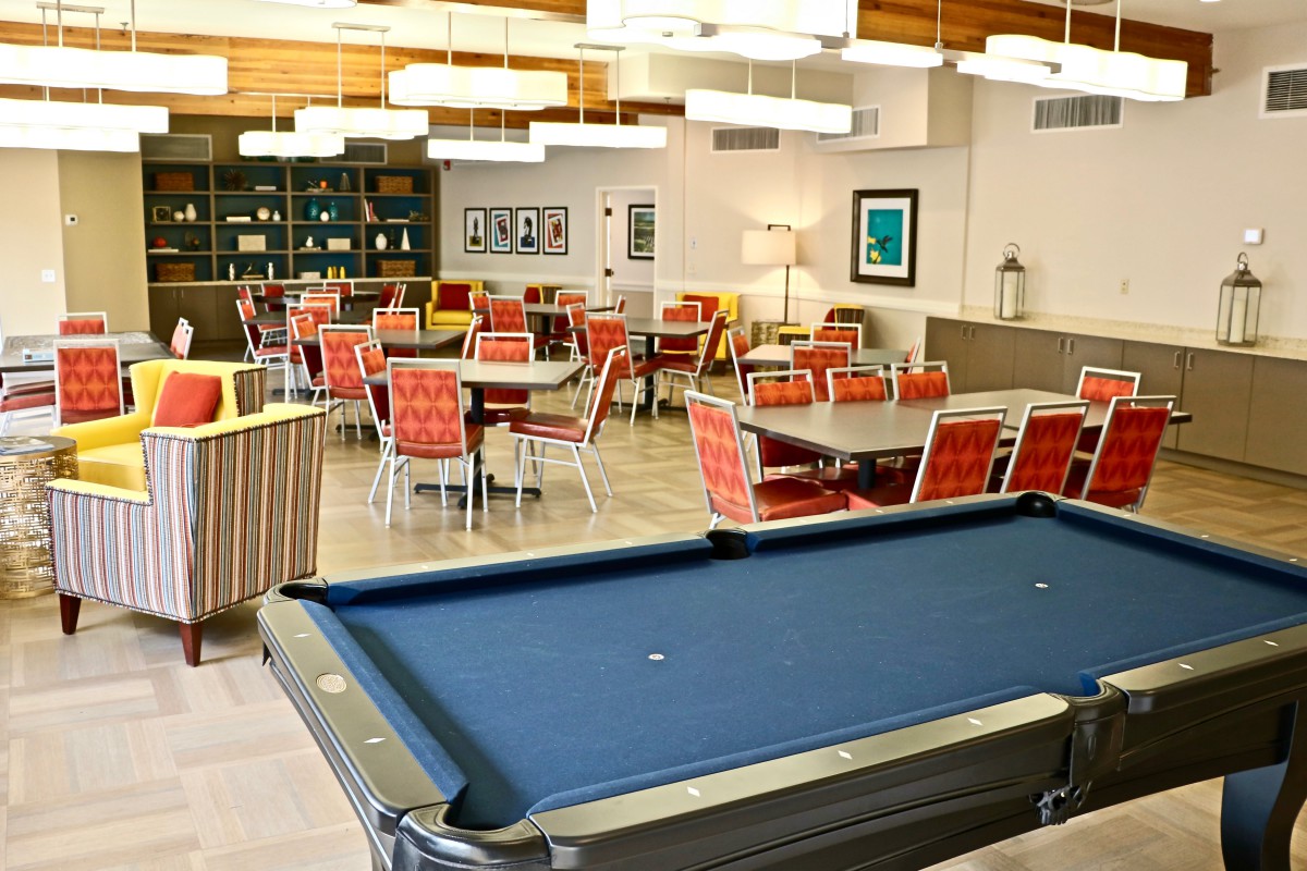 A modern game room featuring a billiard table and a comfortable seating area with vibrant red chairs.