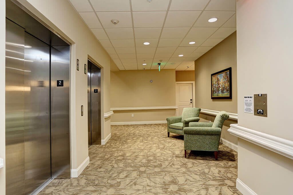A well-lit hallway with elevators and a comfortable seating area.