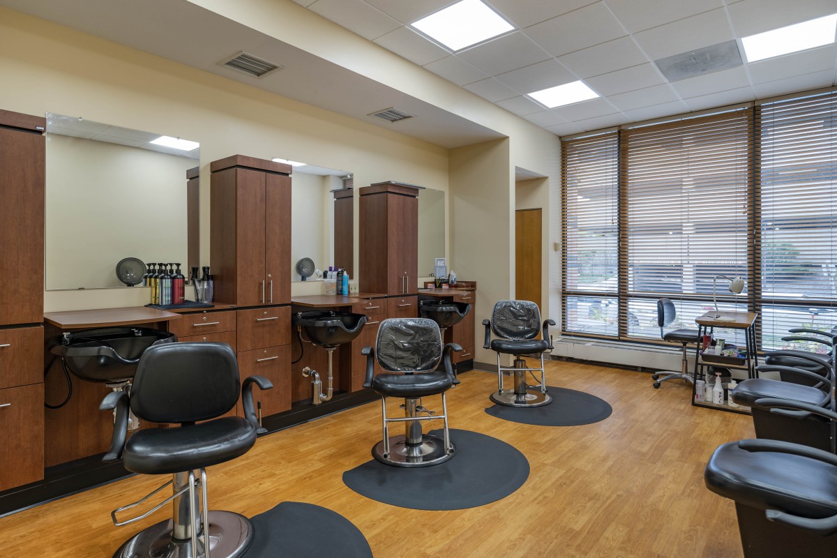An empty hair salon interior with modern chairs and mirrors against a wooden floor.