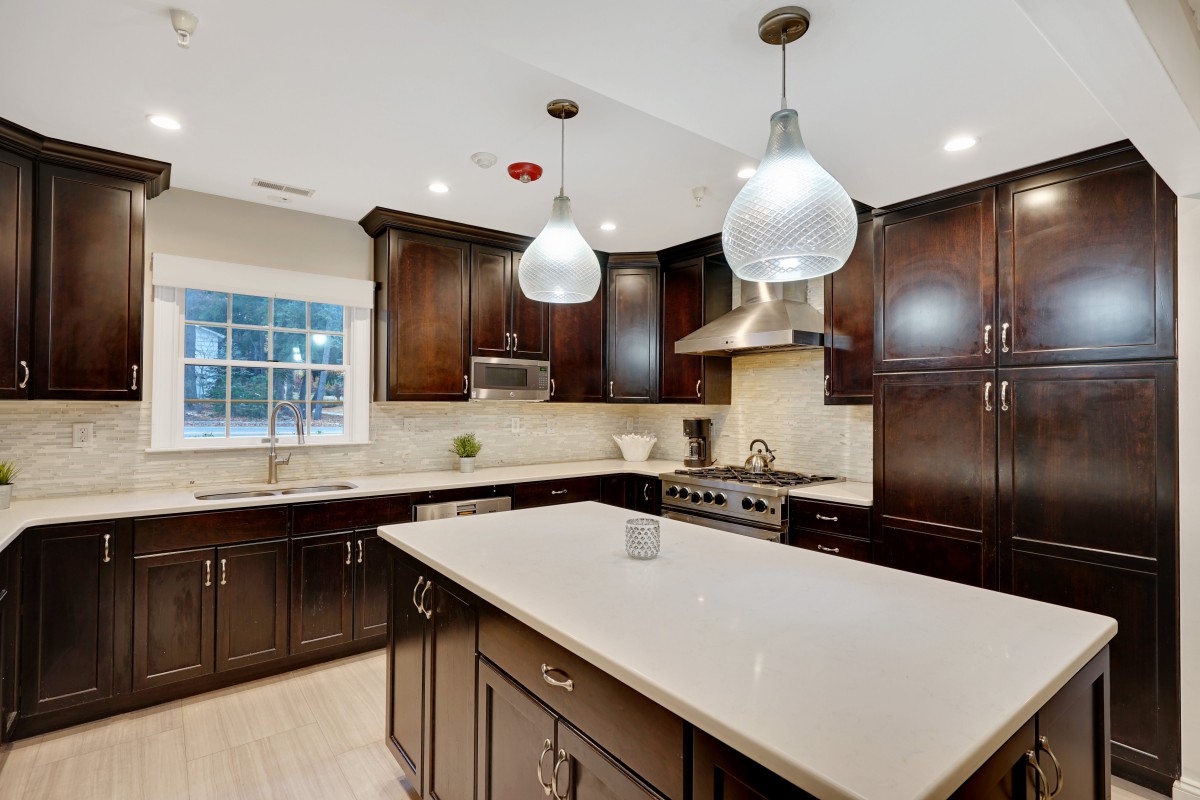 A modern kitchen with dark wood cabinets, an island countertop, and stainless steel appliances.