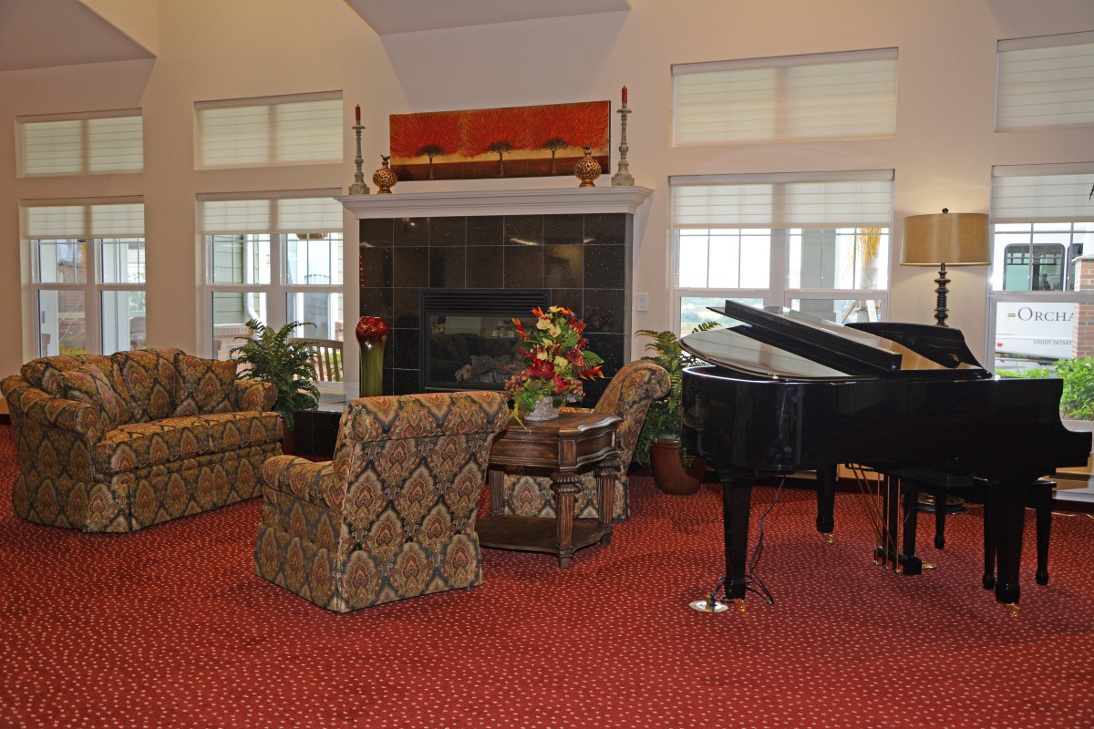 A cozy living room with a grand piano, fireplace, and comfortable seating area.