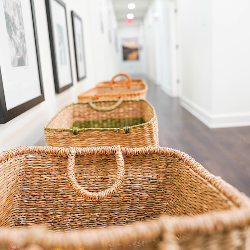 A row of woven baskets in a bright, minimalist hallway adorned with framed artworks.