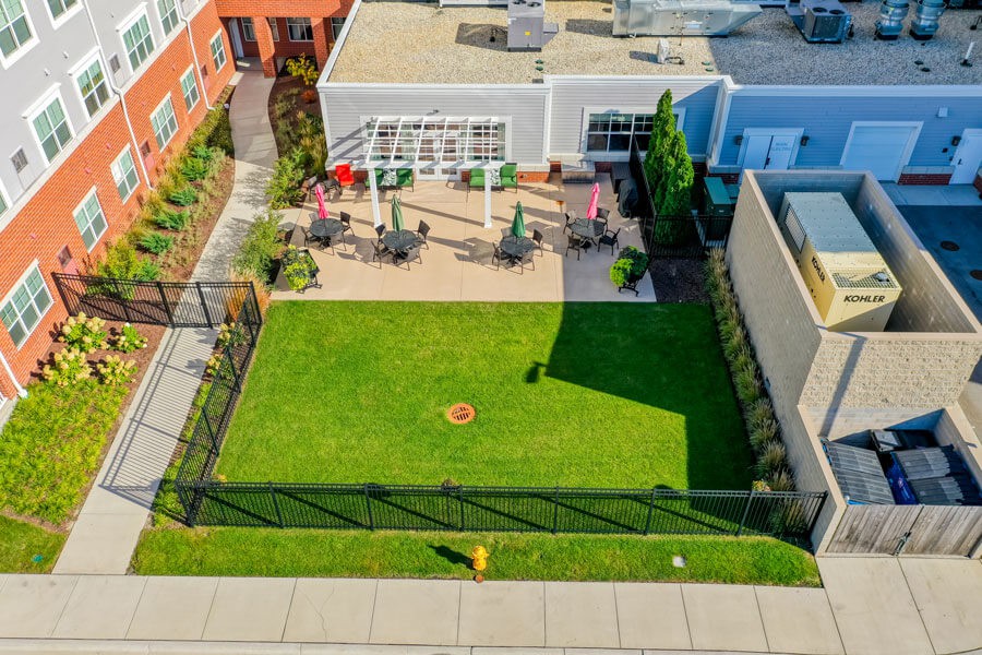 Aerial view of a fenced backyard featuring a green lawn and patio with outdoor seating.