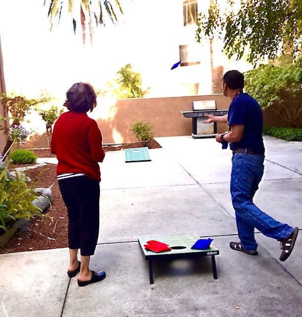 Two people playing a game of cornhole in the backyard.