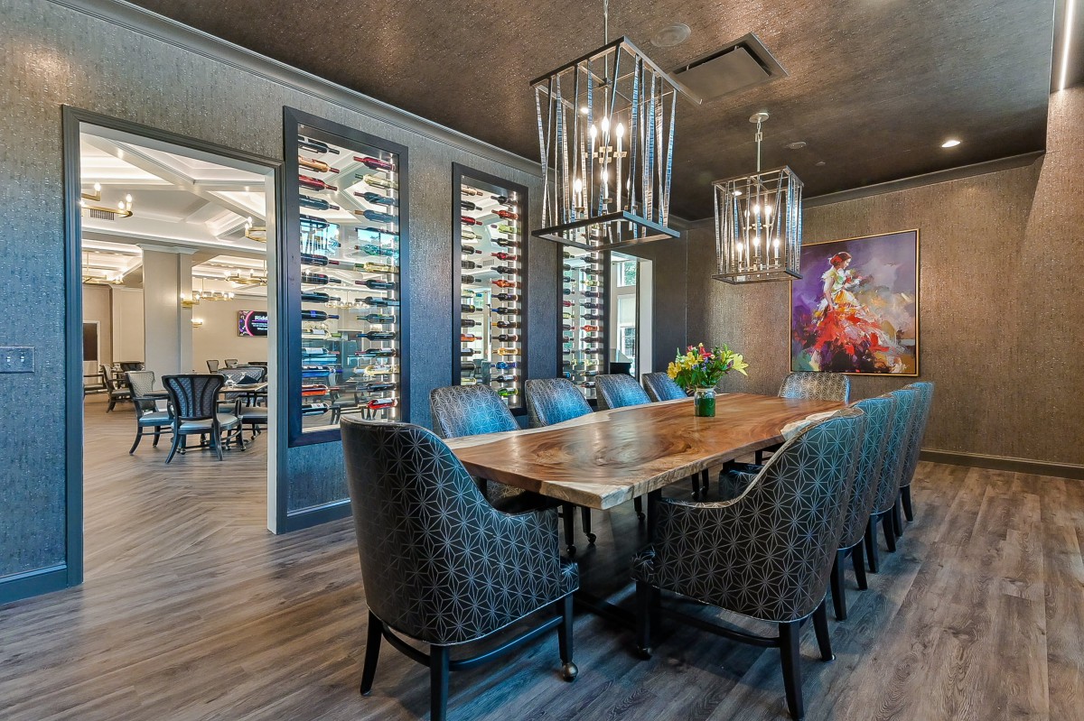 A modern dining room with elegant chandeliers, a wooden table, and stylish chairs.