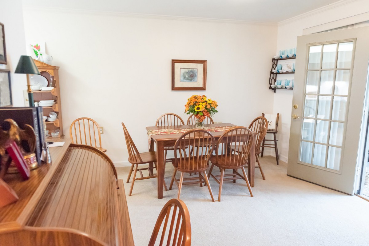 A cozy dining room with a wooden table and chairs, decorated with a vase of flowers.