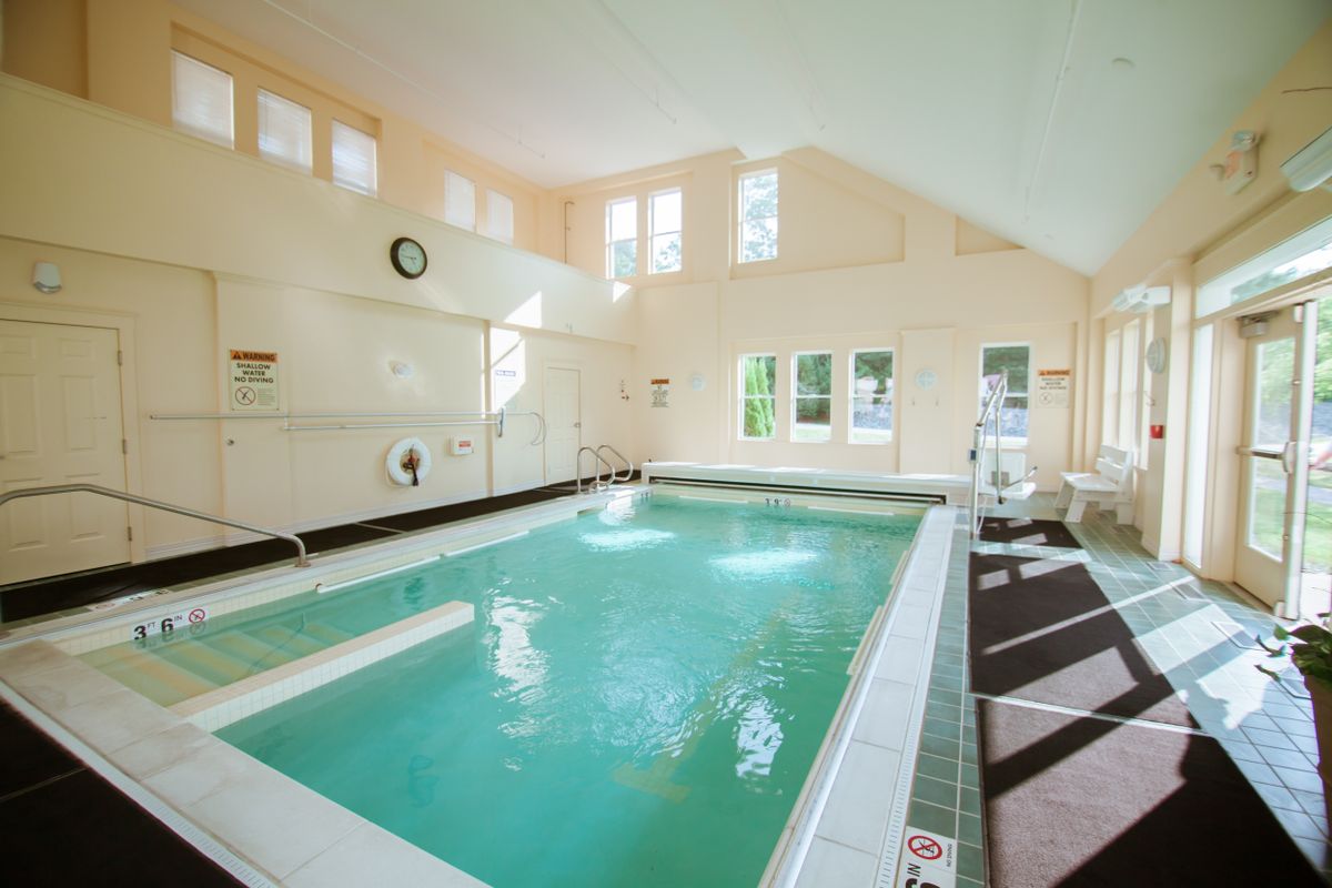 A serene indoor swimming pool area with natural light streaming through the windows.