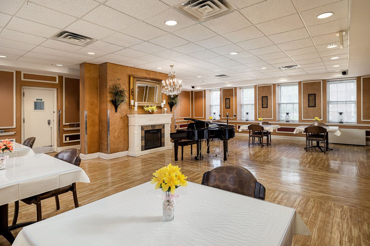 A spacious and elegant room featuring a grand piano, fireplace, and chandelier.