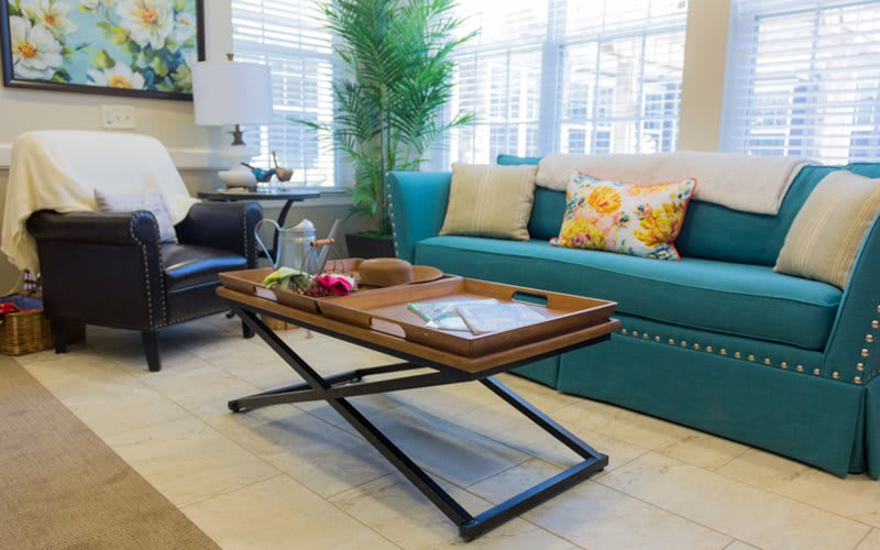 A modern living room with a teal sofa, decorative pillows, and a wooden coffee table with a tray.