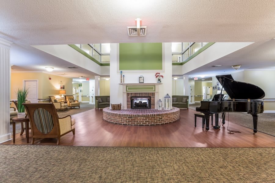 A spacious lobby area featuring a central fireplace, a grand piano, and comfortable seating arrangements.