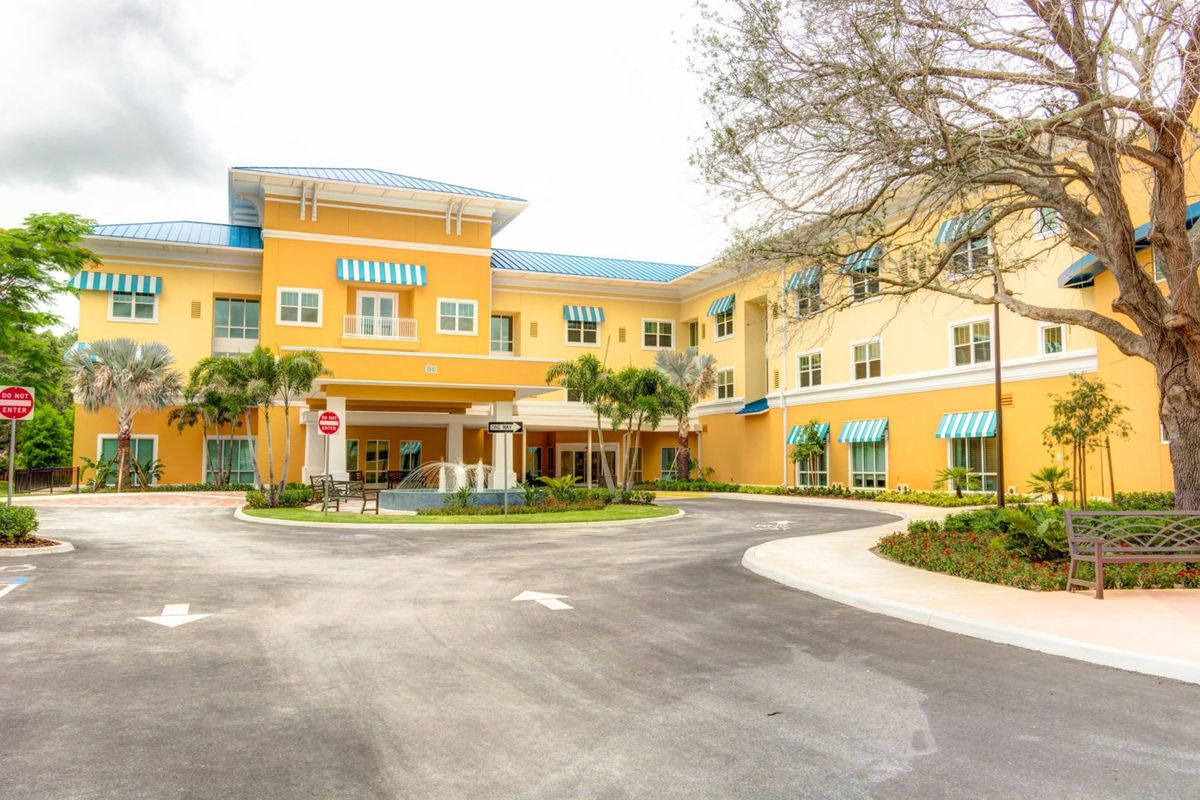 A large yellow residential building with an inviting entrance and landscaped surroundings.