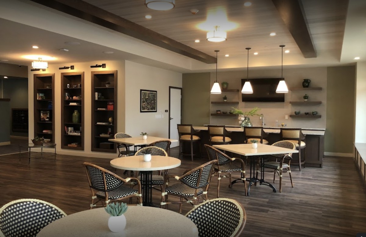 A modern cafe interior with round tables, chairs, and a bar area.