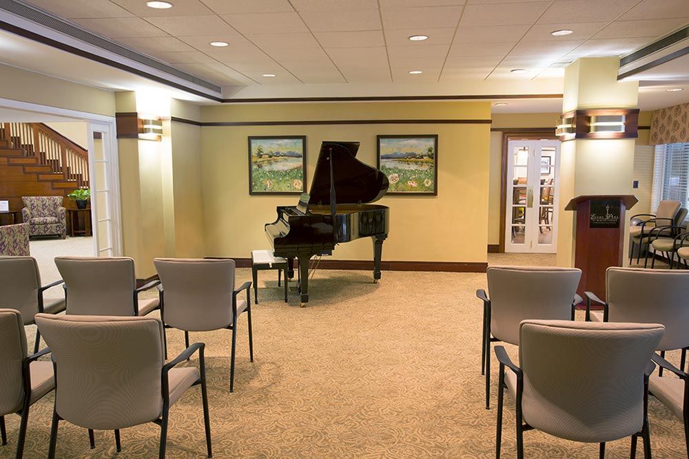 A quiet music room with a grand piano and rows of chairs arranged for an intimate performance.