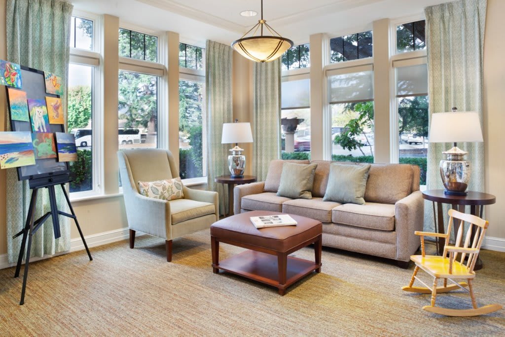 A cozy and well-lit living room with a sofa, armchair, and coffee table near large windows.