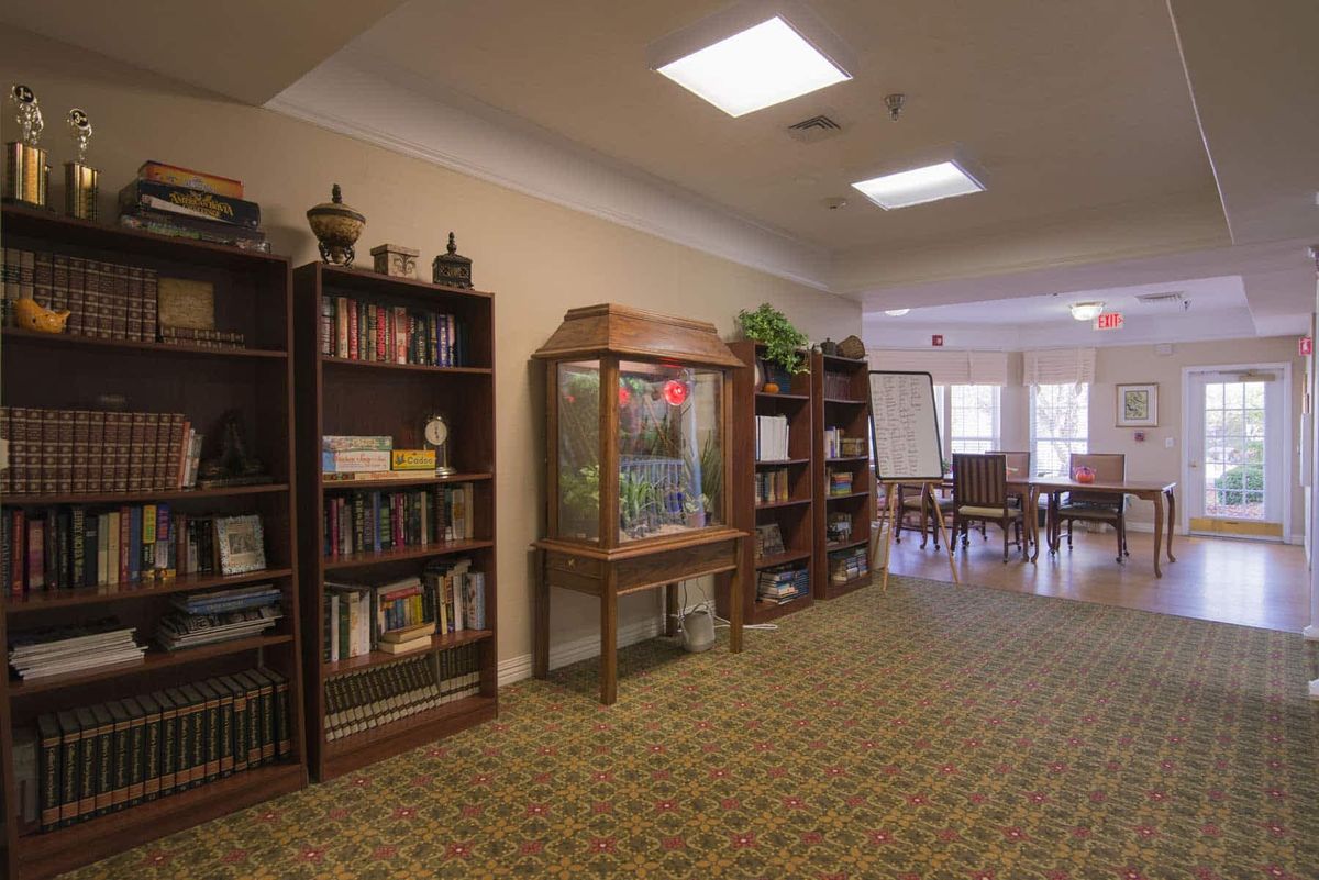 A cozy indoor library with bookshelves, an aquarium, and a reading area.