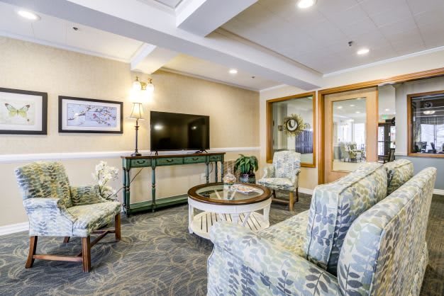 A cozy living room with patterned furniture, a television, and tasteful decor.