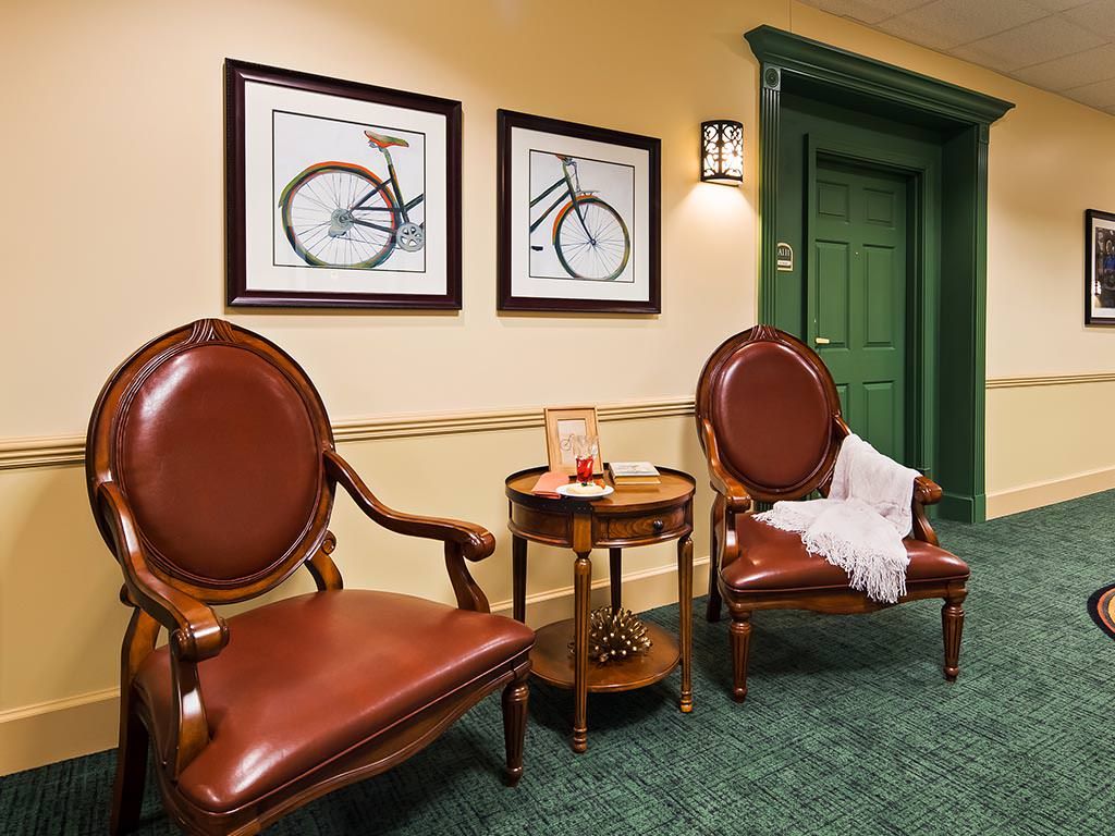 A cozy waiting area featuring two leather chairs, a small round table, and bicycle-themed wall art.