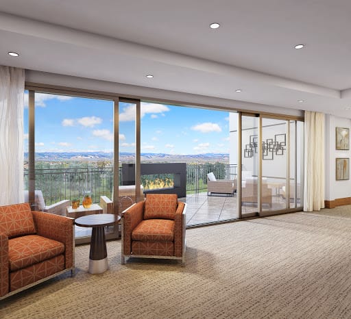 A spacious modern living room with comfortable seating, a fireplace, and large glass doors leading to a patio with scenic views.