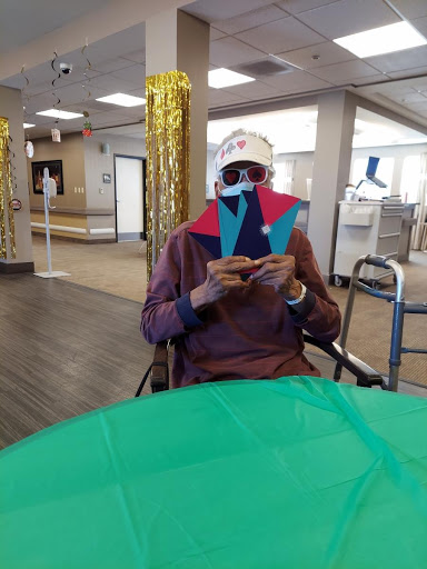 A person seated in a wheelchair holding colorful paper cutouts, enjoying a creative activity indoors.