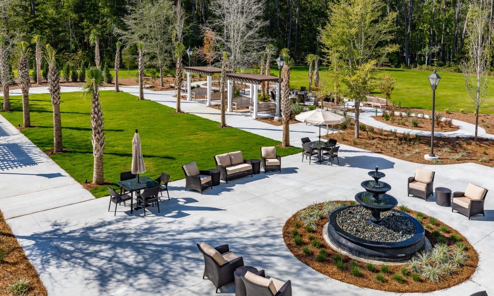 A beautifully landscaped garden featuring outdoor seating and a central fountain.