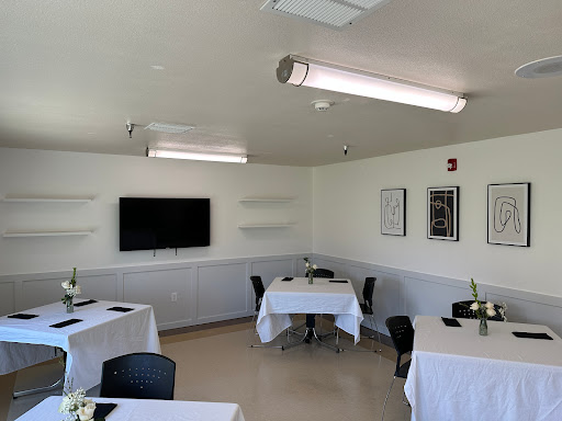 A modern dining area featuring neatly arranged tables and chairs, complemented by a wall-mounted television.