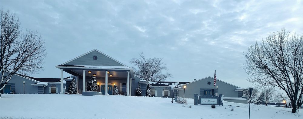 A snowy landscape featuring a house with columns and overcast skies.