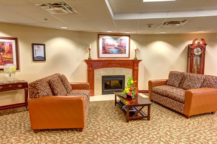 A cozy living room with a fireplace, two sofas, and decorative artwork on the walls.