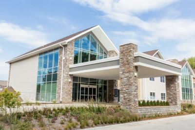 A modern building with a glass facade and stone pillars at the entrance.