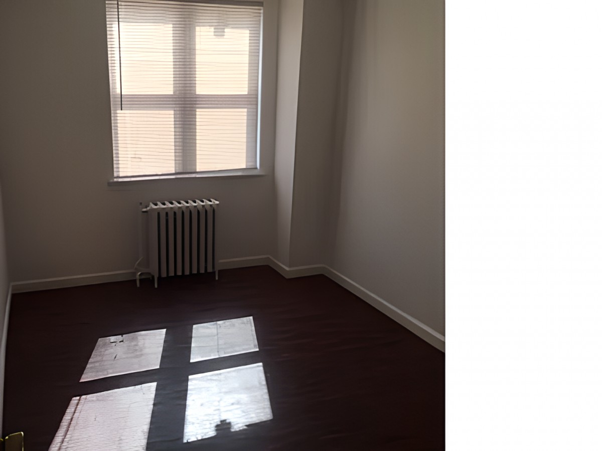An empty room with a window and radiator.