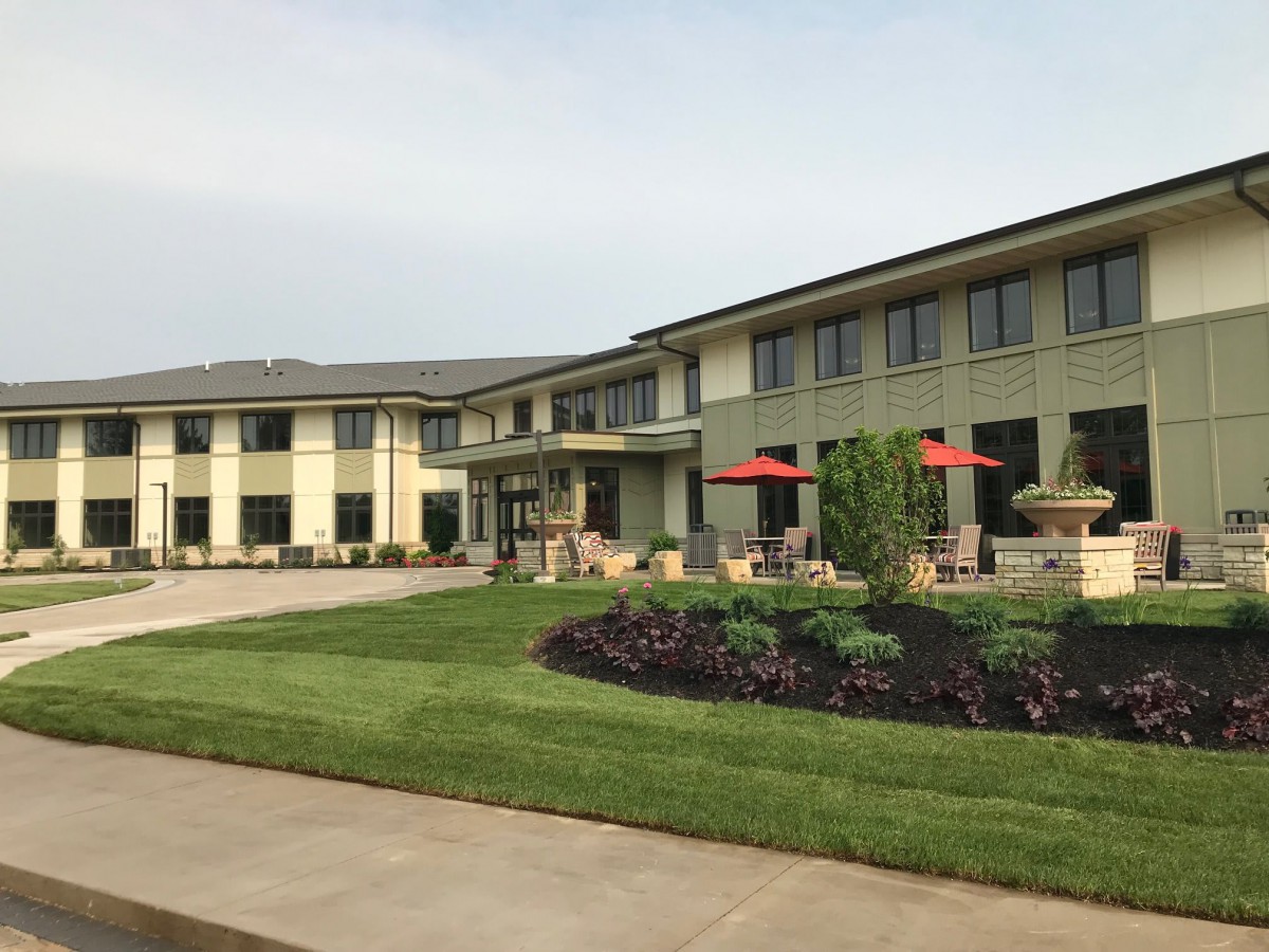 A modern two-story building with a well-maintained lawn and garden.