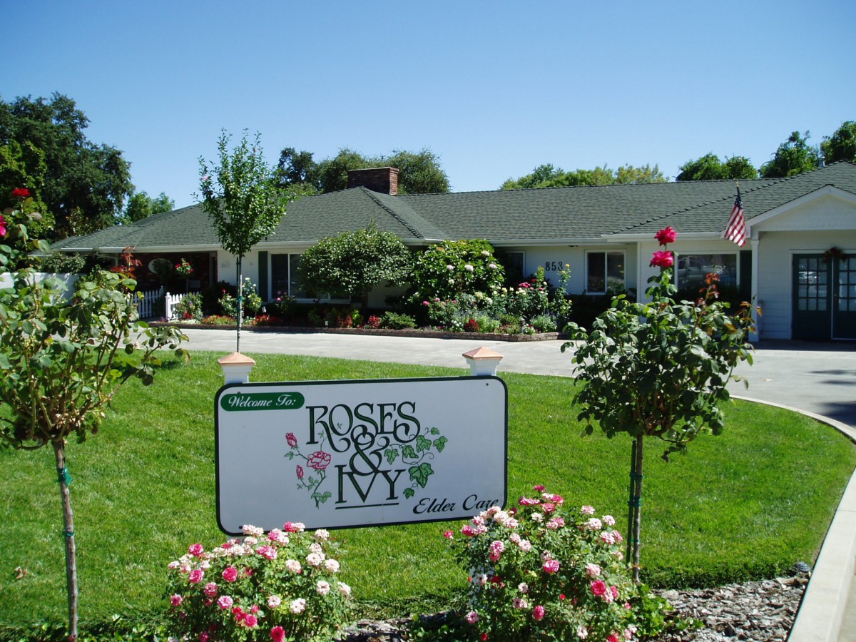 A nursing home named 'Roses and Ivy' surrounded by a well-maintained garden with flowers.