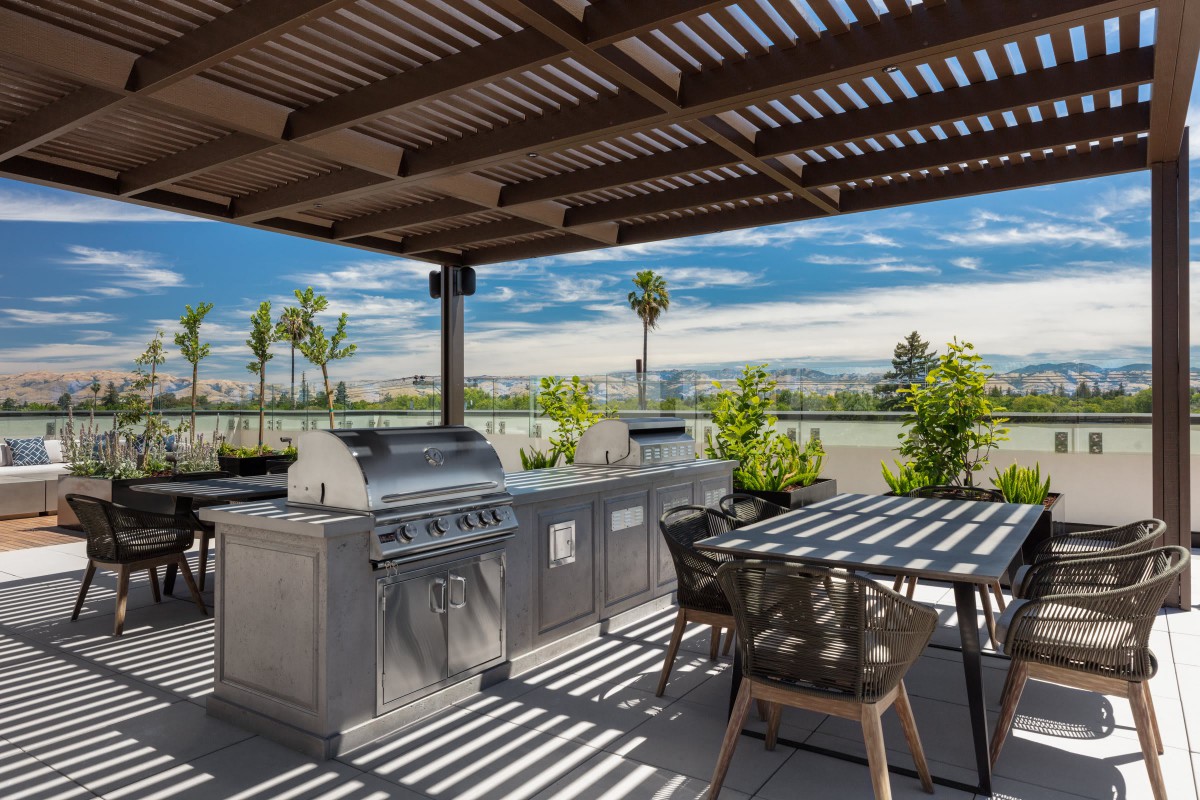 A modern outdoor kitchen under a pergola with stunning scenic views.