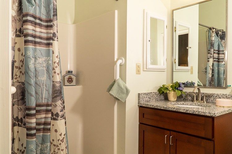 A cozy bathroom with a shower curtain, towel on a rack, and a sink with a cabinet beneath the mirror.