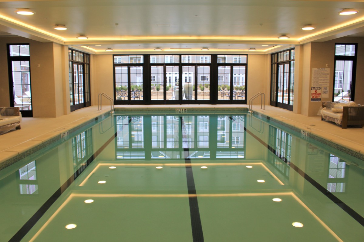 A modern indoor swimming pool with large windows and elegant lighting.