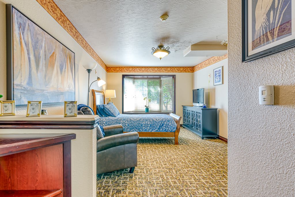 A cozy bedroom featuring a comfortable bed, television, and decorative artwork.