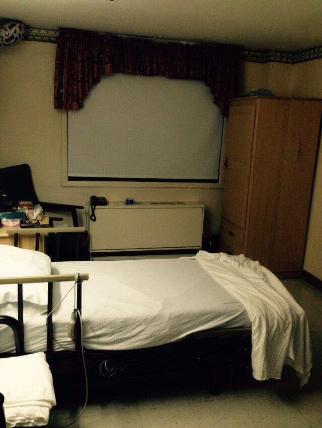 A small bedroom with a bed, wardrobe, and window.
