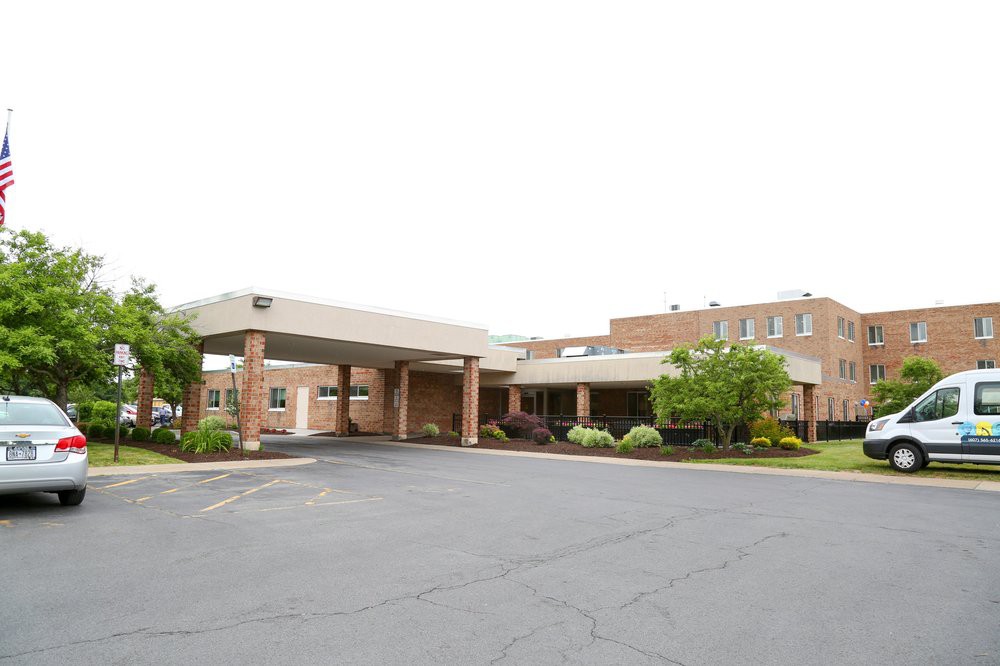 The exterior view of a hospital building with a covered entrance and surrounding greenery.