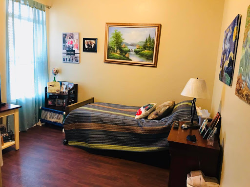 A cozy bedroom featuring a striped bedspread, a wooden desk, and decorative art on the walls.